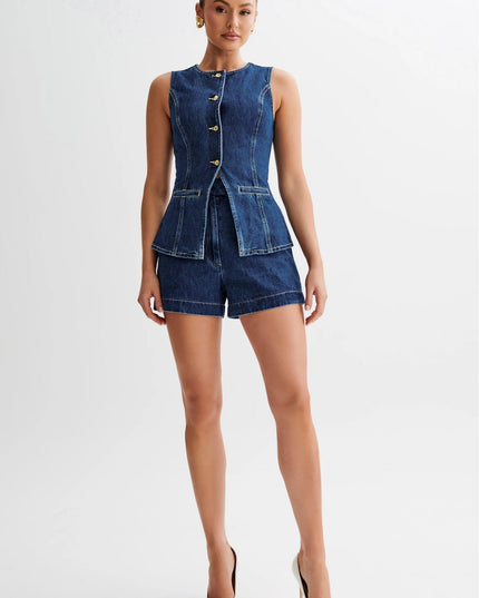 Sleeveless single breasted denim shorts set in dark wash, featuring gold buttons and a peplum waist, paired with white heels.