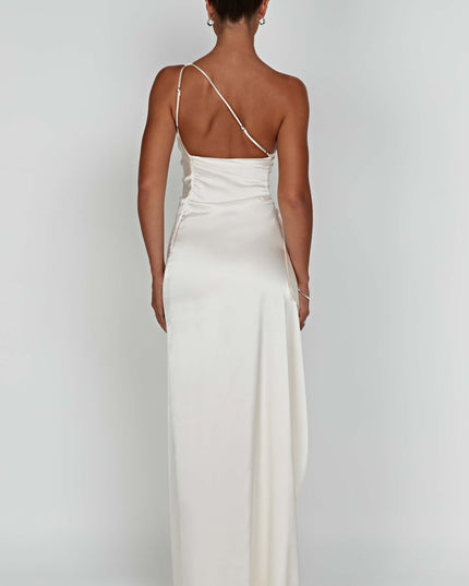 Back view of a women's ivory one shoulder maxi dress, showing the delicate strap and flowing skirt.