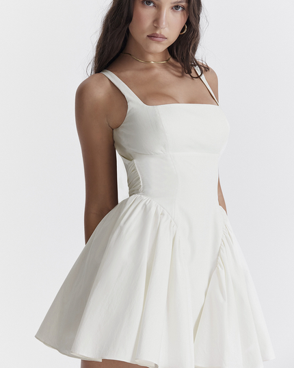 Side profile of a white summer backless mini dress, highlighting the square neck and pleated skirt details.
