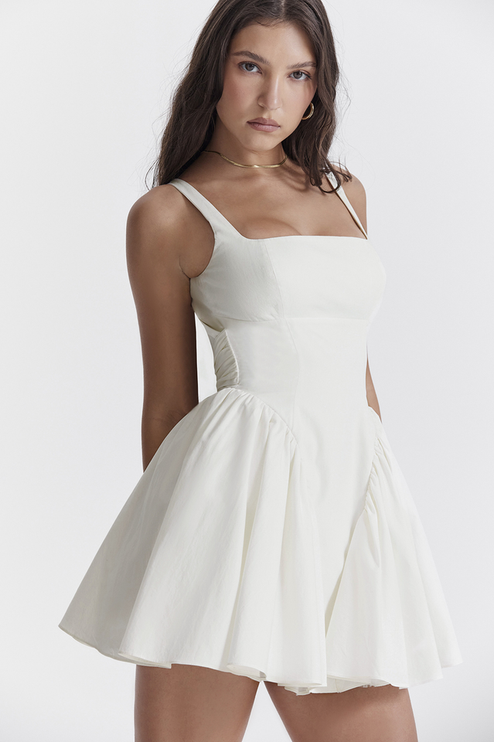 Side profile of a white summer backless mini dress, highlighting the square neck and pleated skirt details.