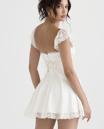 Back view of the white lace cap sleeve mini dress, featuring a corset-style lace-up detail on the back bodice and a full skirt.