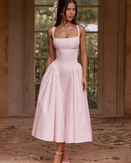 Women's pink gingham square neck midi dress with full pleated skirt, styled with pink heels and hair bow