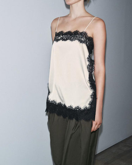 Side view of a women's cream satin camisole mini dress featuring black lace details and delicate straps.