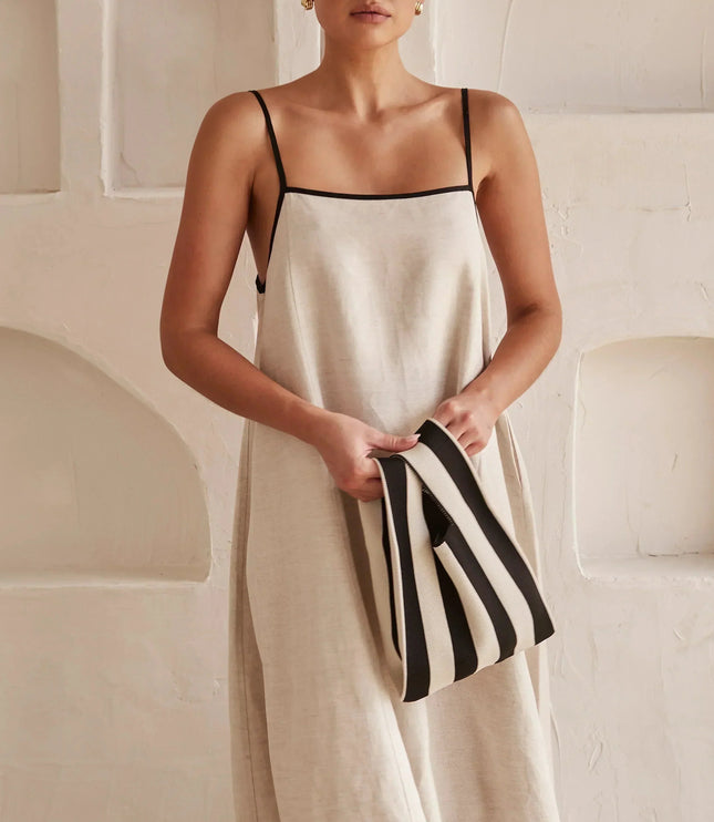 Close-up of the square neck and black spaghetti straps on a light beige women's maxi dress.