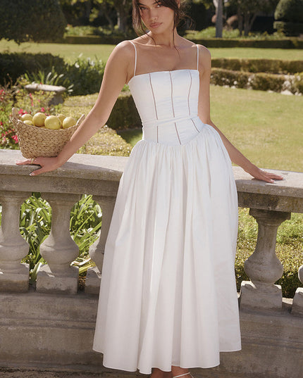 Women's white square neck midi dress with thin straps, standing outdoors with a basket of lemons, wearing white heels.