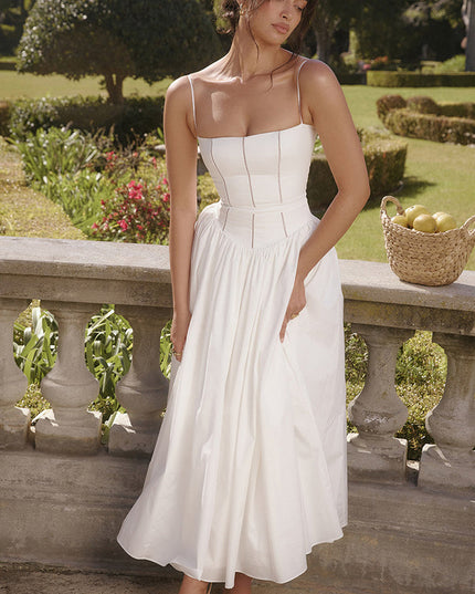 Outdoor shot of women's white sleeveless midi dress, featuring a square neckline and full pleated skirt, with white heels.