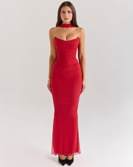 Full length front view of a vibrant red strapless ruched maxi dress with a matching choker and sheer overlay, paired with black heels.