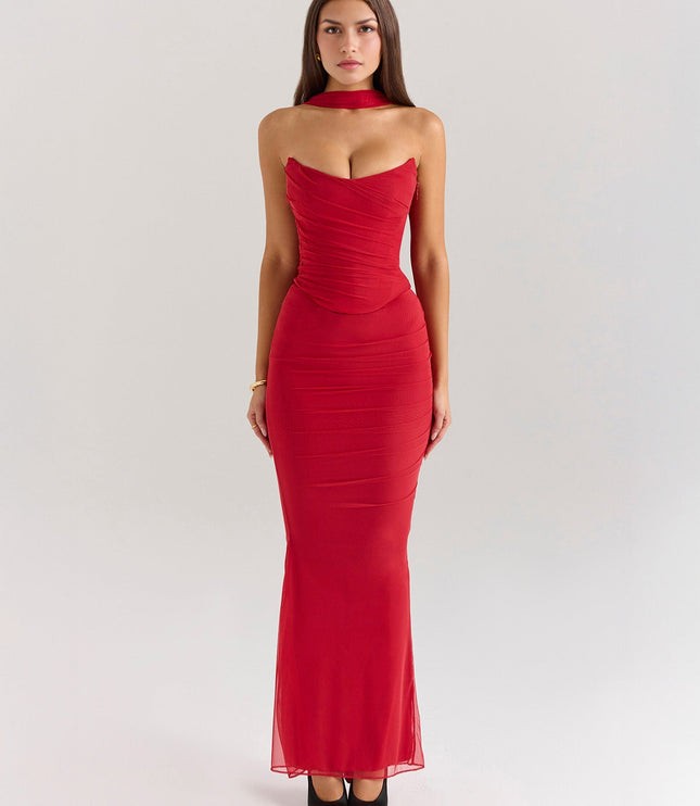 Full length front view of a vibrant red strapless ruched maxi dress with a matching choker and sheer overlay, paired with black heels.
