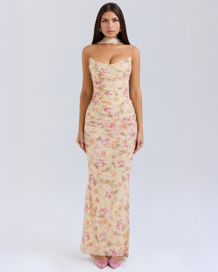 Full-length view of a women's floral strapless ruched maxi dress in light yellow with pink flowers, featuring a matching choker.
