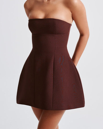 Side profile of a woman wearing a dark brown strapless mini dress, highlighting the structured bodice.