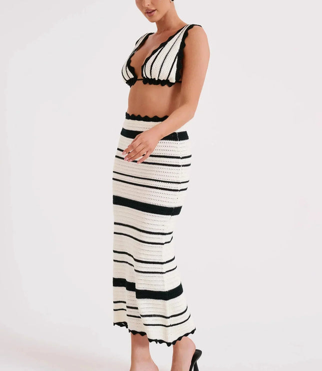 Side view of a women's black and white striped crochet two piece maxi set, showing the fitted skirt and crop top with scalloped trim.