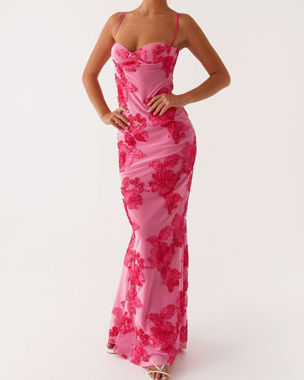 Women's pink floral maxi dress with sweetheart neckline, full body, hands on hips, paired with white heels.