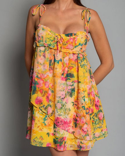 Close-up of the bodice and skirt detail of a women's yellow floral print tie shoulder mini dress.