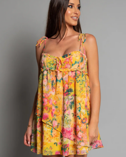 Front view of a women's yellow floral print tie shoulder mini dress with ruffled details.