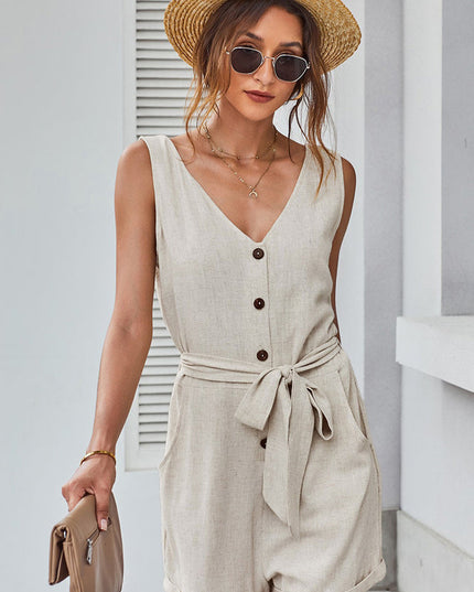 Close-up front view of a women's beige sleeveless V-neck romper with button details and tie waist.