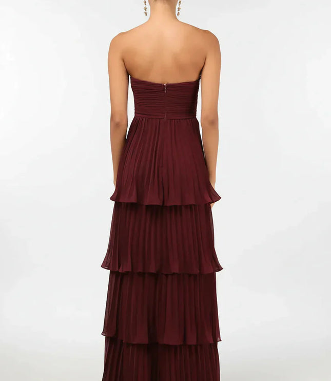 Back view of the women's burgundy strapless tiered pleated maxi dress, showing the full skirt and zipper detail.