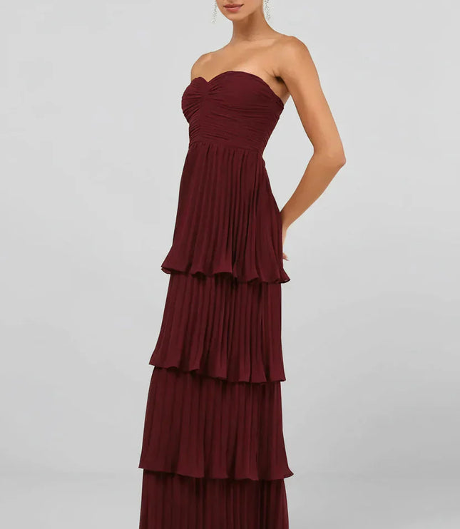 Side profile of the women's strapless tiered pleated maxi dress in burgundy, highlighting the flowing pleats.