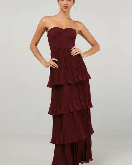 Front view of a women's strapless tiered pleated maxi dress in a rich burgundy color, with a ruched bodice.