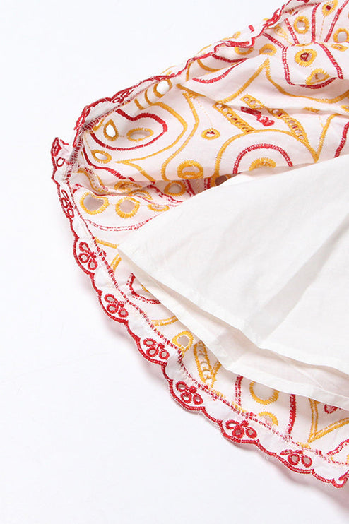 Inside view of the tiered hem of a women's mini dress, the white lining and red and yellow embroidery.
