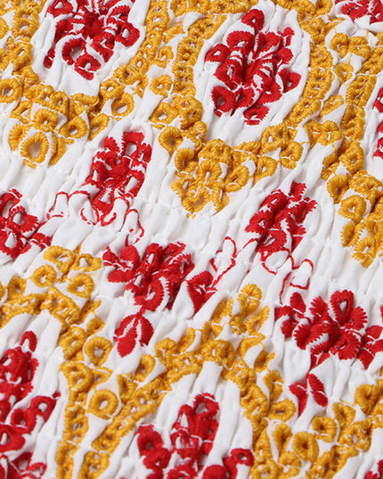 Detailed view of the shirred bodice of a women's summer dress with intricate red and yellow floral embroidery.
