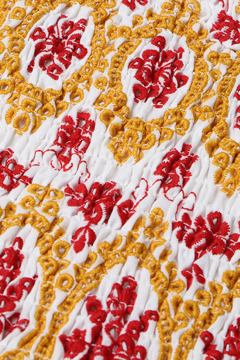 Detailed view of the shirred bodice of a women's summer dress with intricate red and yellow floral embroidery.