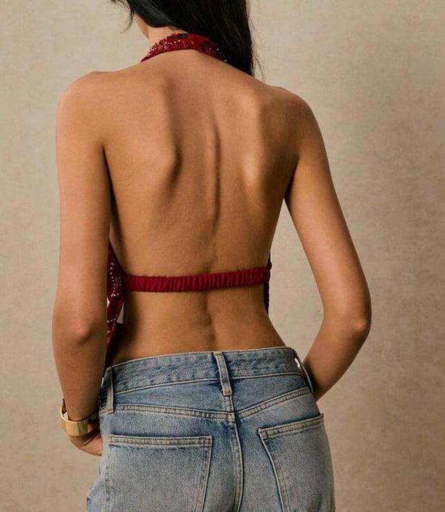 Back view of a women's red sequin halter top, showing the open back design and elastic band, paired with light wash jeans.