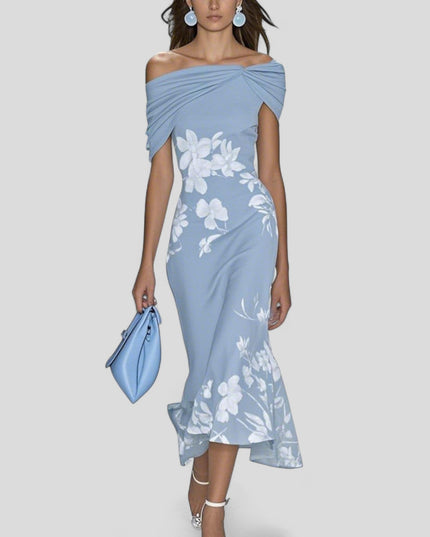 Light blue off-shoulder midi dress with white floral print and elegant trumpet hem, holding a blue handbag.