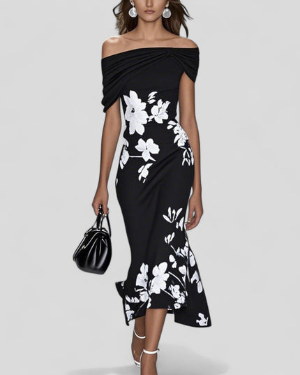 Black off-shoulder midi dress with prominent white floral print and stylish trumpet hem, holding a black handbag.