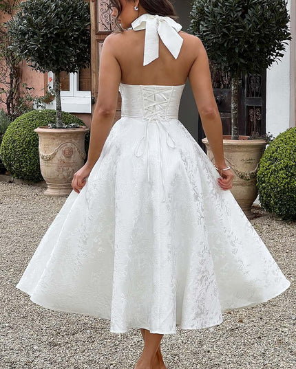Back view of a white jacquard midi dress with a lace-up corset back and halter tie detail.
