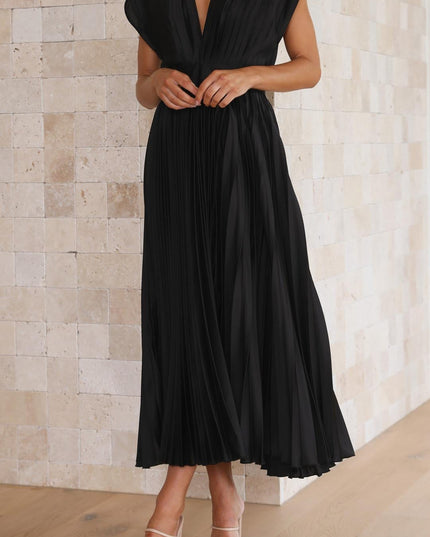 Front detail of the black pleated v-neck midi dress, showing the deep V-neckline and structured short sleeves, with hands clasped.