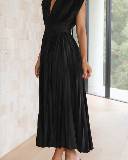 Side profile of the black pleated v-neck midi dress, highlighting the structured bodice and the elegant drape of the pleated skirt.