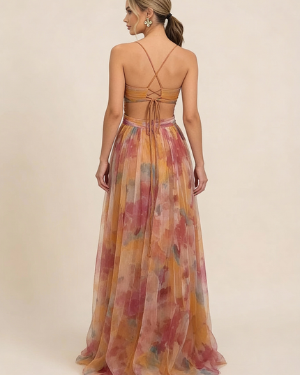 Back view of a women's wedding guest maxi dress with a floral print, criss-cross strap detail, and tie-back closure.