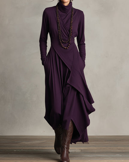 Full-length view of a women's long sleeve draped high neck midi dress in deep plum with pockets, styled with cowboy boots.