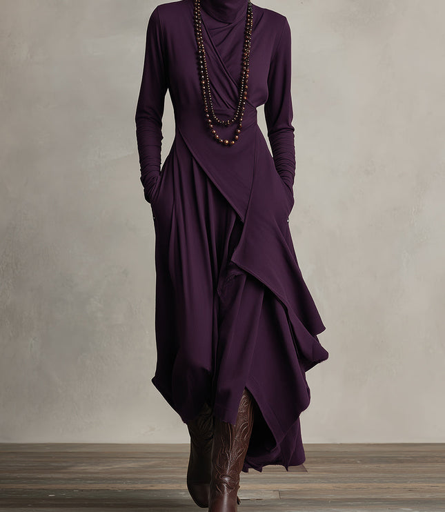 Full-length view of a women's long sleeve draped high neck midi dress in deep plum with pockets, styled with cowboy boots.